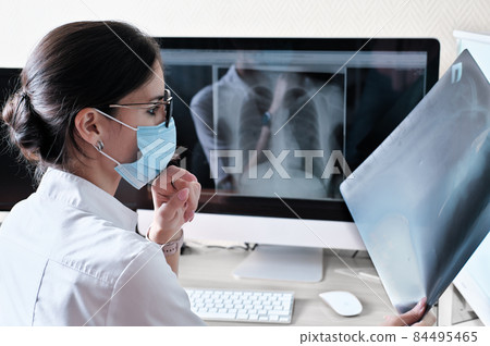 Asian woman doctor radiologist examining film x-ray image. Analyze a progress of lung disease. Health care concept, radiology department of clinic or hospital Asian woman doctor radiologist examining film x-ray image. Analyze a progress of lung disease. Health care concept, radiology department of clinic or hospital 84495465