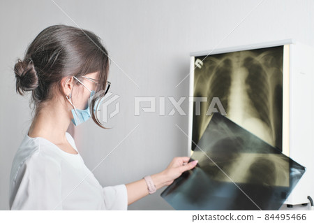 mixed raced woman doctor radiologist checking film x-ray image from machine. Analyze a progress of disease. Health care concept. modern diagnostics methods. 84495466