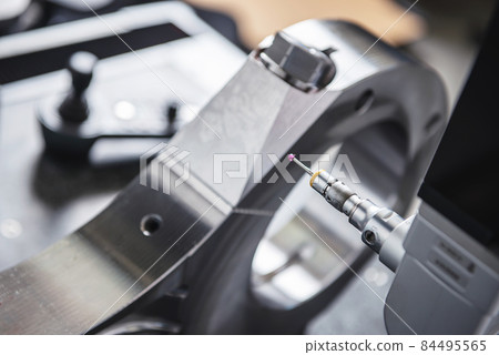 A heavy industrial worker in a factory works with metal on angle grinders while hot sparks are produced as a result. 84495565