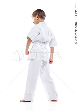 Back view portrait of little boy in white kimono, martial art sportsman posing isolated over white background Back view portrait of little boy in white kimono, martial art sportsman posing isolated over white background 84495936