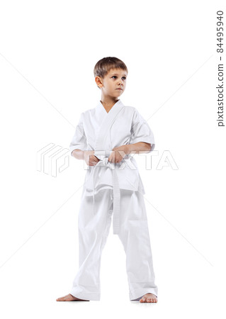 Cropped portrait of little boy in white kimono, martial arts sportsman posing isolated over white background Cropped portrait of little boy in white kimono, martial arts sportsman posing isolated over white background 84495940