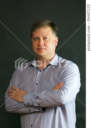 An adult Caucasian man of Slavic appearance in a blue shirt on a black background An adult Caucasian man of Slavic appearance in a blue shirt on a black background 84497225