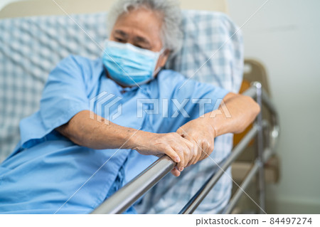 Asian senior or elderly old woman patient wearing mask for protect coronavirus lie down handle the rail bed with hope on a bed in the hospital Asian senior or elderly old woman patient wearing mask for protect coronavirus lie down handle the rail bed with hope on a bed in the hospital 84497274