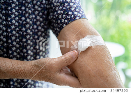 Asian senior or elderly old lady woman patient show cotton wool stop bleeding, after blood drawing testing for annually physical health check up to check cholesterol, blood pressure, and sugar level. 84497293