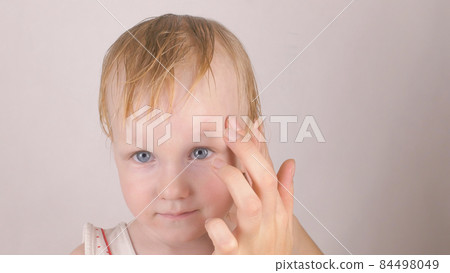 Mother treats a scar wound on the forehead of her little caucasian daughter with a healing cream against allergies and wound healing, close-up Mother treats a scar wound on the forehead of her little caucasian daughter with a healing cream against allergies and wound healing, close-up 84498049