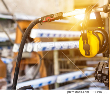 Safety noise at the workplace, yellow headphones against noise hang in the workshop for the manufacture of PVC windows, accident prevention Safety noise at the workplace, yellow headphones against noise hang in the workshop for the manufacture of PVC windows, accident prevention 84498100