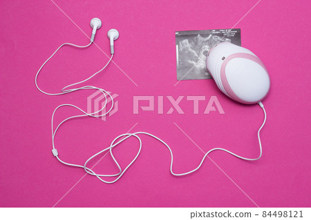 Fetal doppler with headphones for listening to the baby s heartbeat in pregnant women and a picture of the ultrasound of pregnancy, close-up, pink background Fetal doppler with headphones for listening to the baby s heartbeat in pregnant women and a picture of the ultrasound of pregnancy, close-up, pink background 84498121