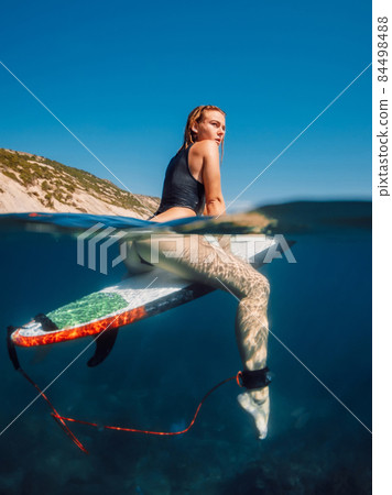 Sexy surfer woman on surfboard in blue ocean, split shot Sexy surfer woman on surfboard in blue ocean, split shot 84498488