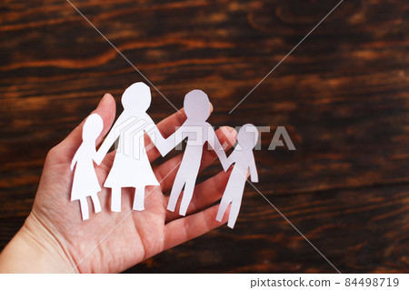 human hand holding happy paper cut family on a brown wooden background human hand holding happy paper cut family on a brown wooden background 84498719