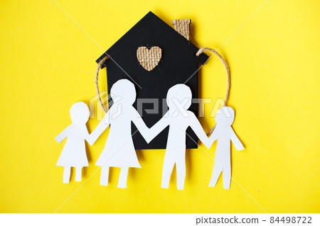 Happy paper cut family holding hands on yellow background near little toy house 84498722