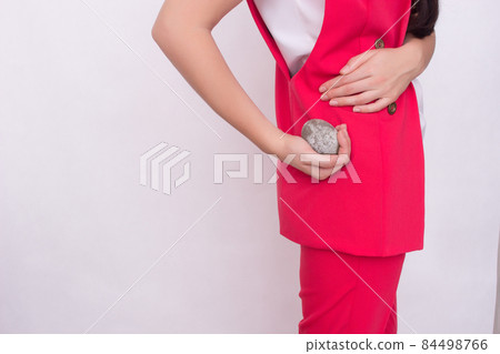 girl on a white background holds a stone in her hand near the kidney, the concept of kidney stones, copy space, disease girl on a white background holds a stone in her hand near the kidney, the concept of kidney stones, copy space, disease 84498766