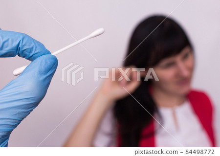 A cotton swab in the hand of the doctor, the girl holds on to the ear, a sulfur plug in the ear, fighting ear plugs, close-up, medical A cotton swab in the hand of the doctor, the girl holds on to the ear, a sulfur plug in the ear, fighting ear plugs, close-up, medical 84498772