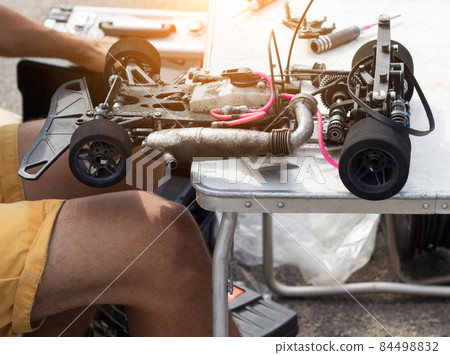 The participant checks and adjusts the radio-controlled car before the start of the competition, close-up, self-made sports competitions 84498832