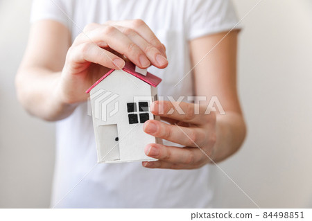 Woman hand holding toy model house isolated on white background. Real estate mortgage property insurance dream home concept. Offer of purchase rental house, family life, business real estate 84498851