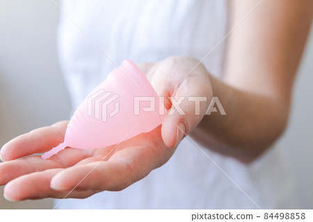 Woman hand holding pink menstrual cup isolated on white background. Woman modern alternative eco gynecological hygiene in menstruation period. Container for blood in girl hand 84498858
