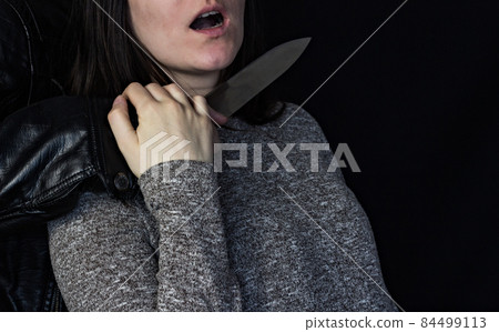 Man holding a knife at the girl's throat, black background Man holding a knife at the girl's throat, black background 84499113