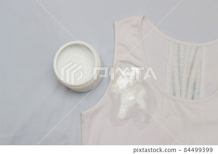 Spot on a white T-shirt filled with stain remover, fighting stains on clothes, white T-shirt, close-up, container with stain remover Spot on a white T-shirt filled with stain remover, fighting stains on clothes, white T-shirt, close-up, container with stain remover 84499399