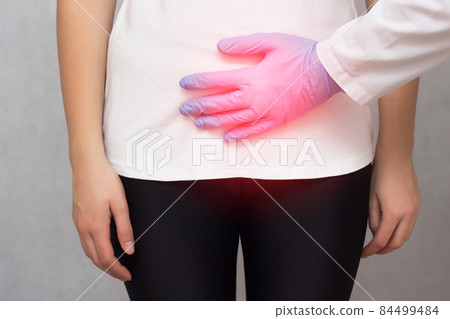 A doctor in medical gloves holds a girl by the lower abdomen which has problems with menstruation and pain, carcinoma, close-up, gynecology 84499484