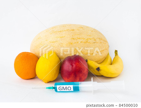 Fruits on a white background bananas, orange, melon, lemon and nectarine, next is a syringe with gmo and nitrates, genetically modified organism, fruit 84500010