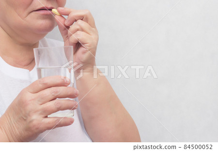 Woman drinking potassium iodide tablet and levothyroxine sodium, for the treatment of the thyroid gland, close-up, copy space Woman drinking potassium iodide tablet and levothyroxine sodium, for the treatment of the thyroid gland, close-up, copy space 84500052