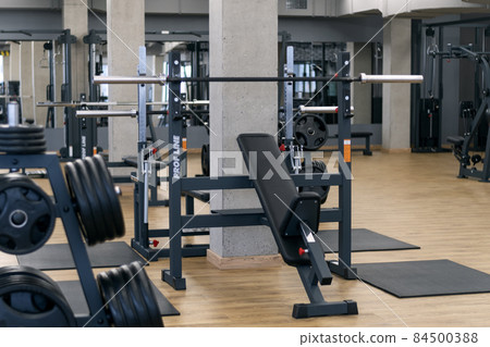 Modern gym with various equipment for training. Sports simulators and dumbbells. Modern gym with various equipment for training. Sports simulators and dumbbells. 84500388