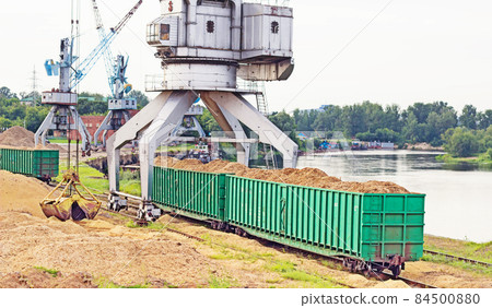 The port crane makes loading of wood chips into the freight cars of the train, loading 84500880