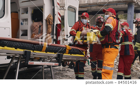 Diverse paramedics preparing survivor for transportation 84501416