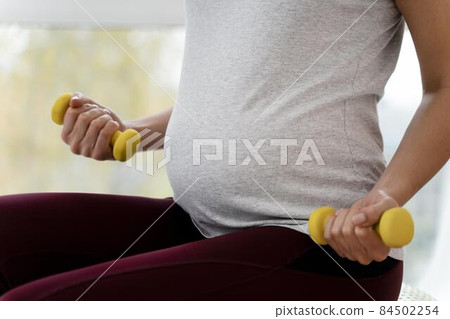 pregnant woman using yellow weights. High quality photo pregnant woman using yellow weights. High quality photo 84502254