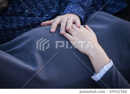 Men's hand rests on the abdomen of a pregnant woman Men's hand rests on the abdomen of a pregnant woman 84502568