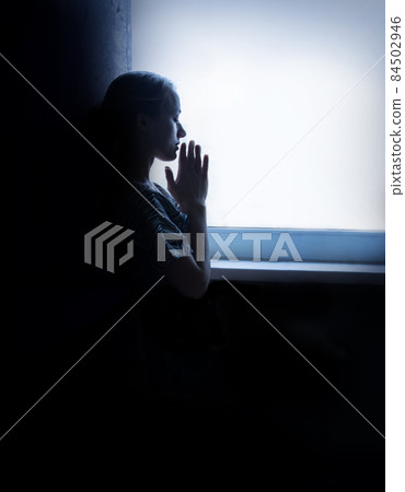 Young girl prays at the window Young girl prays at the window 84502946
