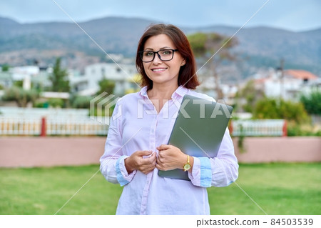 Outdoor portrait of a confident positive woman with a laptop in her hands Outdoor portrait of a confident positive woman with a laptop in her hands 84503539