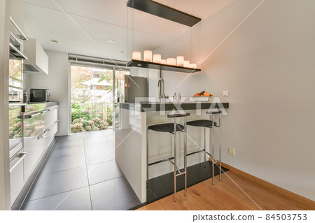Interior of minimalist style kitchen with modern appliances in light apartment Interior of minimalist style kitchen with modern appliances in light apartment 84503753