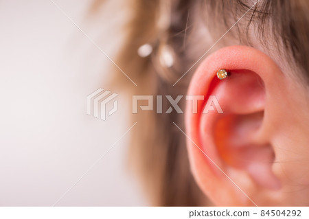 Professional placing the jewel of piercing on the ear with ball. Tragus type. Professional placing the jewel of piercing on the ear with ball. Tragus type. 84504292
