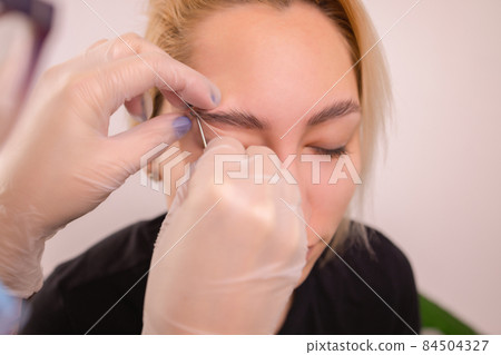 Professional placing the jewel of piercing on the temple on the head with ball. Tragus type. Professional placing the jewel of piercing on the temple on the head with ball. Tragus type. 84504327