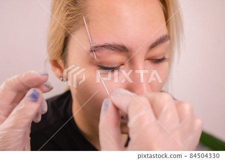 Professional placing the jewel of piercing on the temple on the head with ball. Tragus type. Professional placing the jewel of piercing on the temple on the head with ball. Tragus type. 84504330
