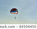 Parachute with flying man against blue sky background 84504450