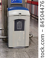 A gray plastic waste basket in a public place 84504476