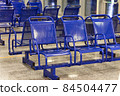 Empty blue plastic chairs in a public place 84504477