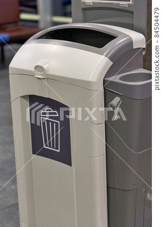 A gray plastic waste basket in a public place A gray plastic waste basket in a public place 84504479