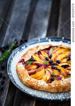 Rustic open pie (galette) with peach and berry 84504579