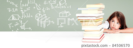 Young cute girl sitting at the table and reading a book 84506570