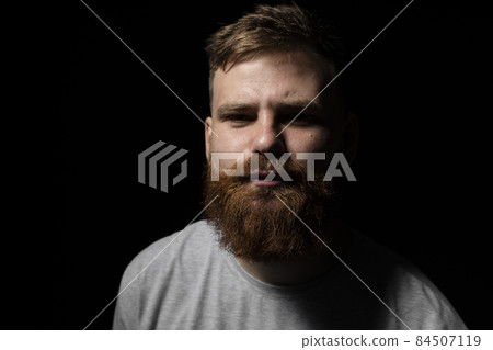Close-up portrait of a handsome a brunette brutal bearded man in a grey t-shirt. Stylish and handsome man with a beard. Close-up portrait of a handsome a brunette brutal bearded man in a grey t-shirt. Stylish and handsome man with a beard. 84507119