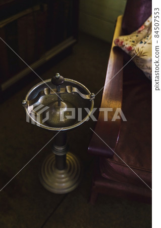 Vintage metal ashtray beside an armchair in historical home Vintage metal ashtray beside an armchair in historical home 84507553