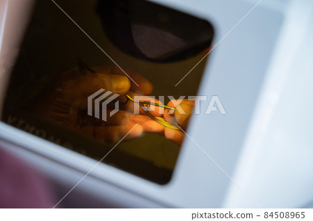 The technician solders the metal frame of the glasses. 84508965