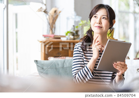 一位女士在客廳操作平板電腦 一位女士在客廳操作平板電腦 84509704