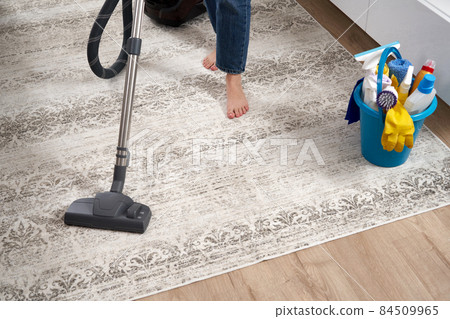 Woman cleaning the carpet with vacuum cleaner in the living room 84509965