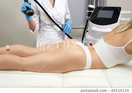 professional cosmetologist using ultrasound cavitation machine on a female buttock professional cosmetologist using ultrasound cavitation machine on a female buttock 84510154