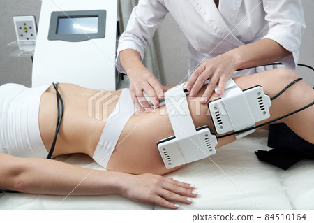 Beautiful woman getting electro stimulation therapy. Laser lipo equipment. Cosmetic fat reduce treatment. Anti cellulite procedure Beautiful woman getting electro stimulation therapy. Laser lipo equipment. Cosmetic fat reduce treatment. Anti cellulite procedure 84510164