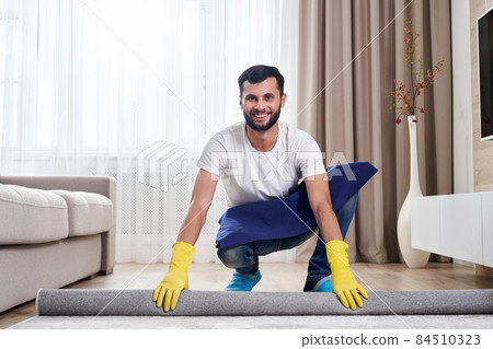 Close up of man unrolling carpet. Cleaning service concept 84510323