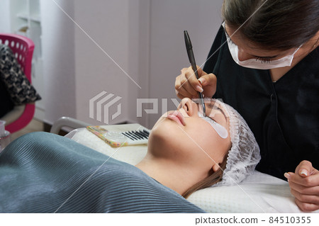 Eyelash Extension Procedure. Woman Eye with Long Eyelashes 84510355